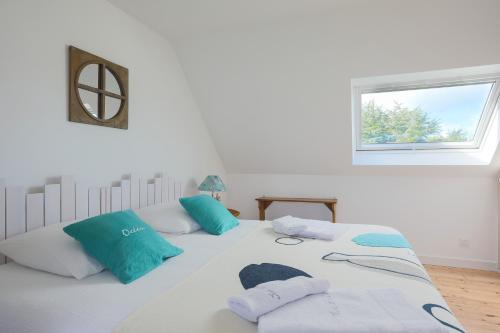 a white bed with blue pillows and a window at Ker Lotig in Locquirec