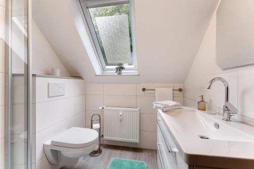 a bathroom with a toilet and a sink and a window at Appartement Skagen in Glücksburg