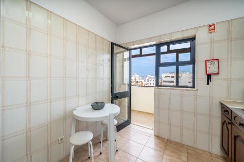 a kitchen with a small table and a window at Candirocha A8 in Portimão