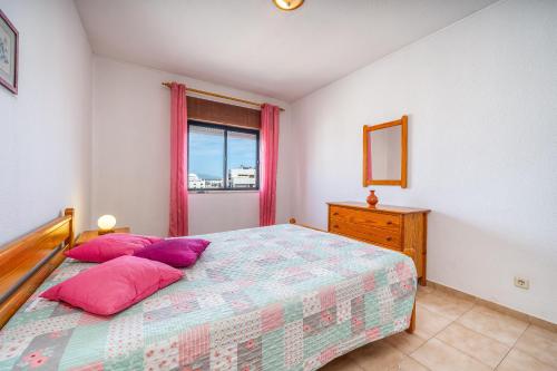 a bedroom with a bed with pink pillows and a window at Candirocha A8 in Portimão