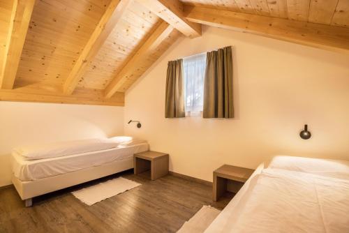 two beds in a room with wooden ceilings at Apartment Sis Residence Bun Ste in San Vigilio Di Marebbe