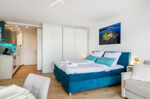 a bedroom with a blue bed and a kitchen at Ferienwohnung Mainaublick in Uhldingen-Mühlhofen