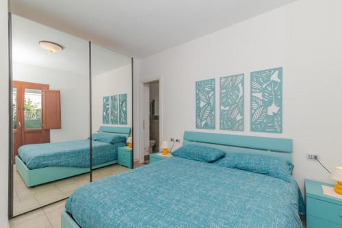 a bedroom with two blue beds and a mirror at Villetta Giardino e Piscina in Porto San Paolo