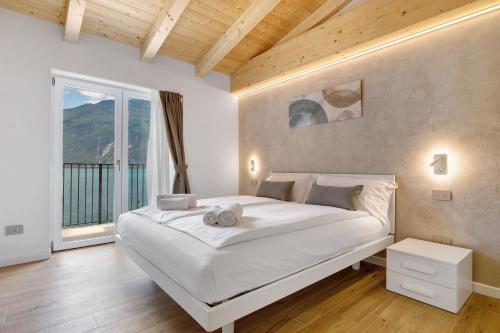 a bedroom with a large white bed and a large window at Jacky's Apartments in Limone sul Garda