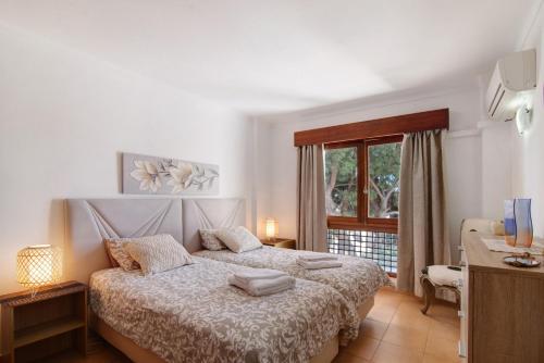 a white bedroom with a bed and a window at Tenis Golfmar in Vilamoura