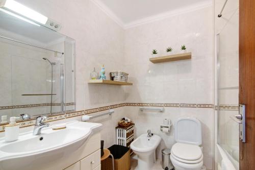 a white bathroom with a sink and a toilet at Tenis Golfmar in Vilamoura