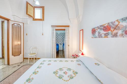 a white bedroom with a bed and a chair at Cod 278 al centro del paese in Ugento