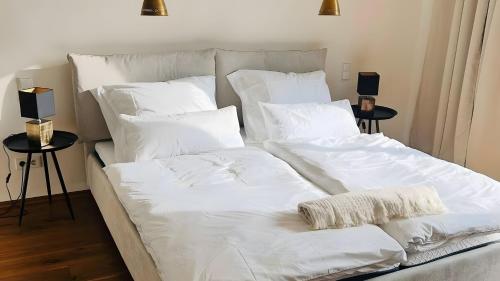 a large white bed with white sheets and pillows at Traumhaus mit herrlichem Graz Blick in Graz