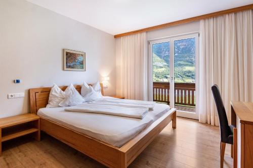 a bedroom with a bed and a desk and a window at Niedermaierhof in Kastelbell-Tschars