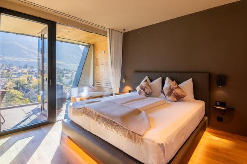 a bedroom with a large bed with a large window at Levita Living Freiheit in Tirolo