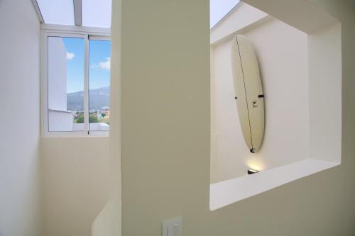 a white bathroom with a surfboard in a mirror at Mojo Surf Yoga House in La Orotava