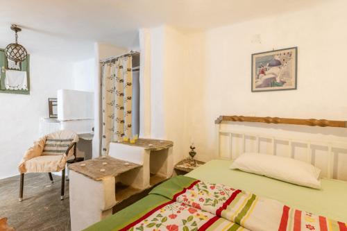 a bedroom with a bed and a table and a chair at Haus Nikos - Tinos - Arnados in Arnados