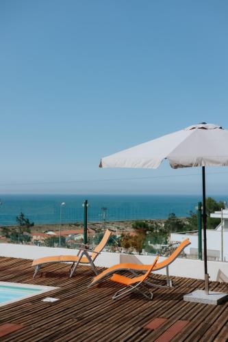 a couple of chairs and an umbrella on a deck at Casa das Camarinhas in Murtinheira