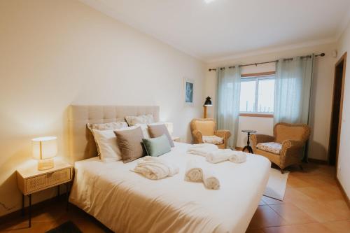 a bedroom with a large white bed with towels on it at Casa das Camarinhas in Murtinheira