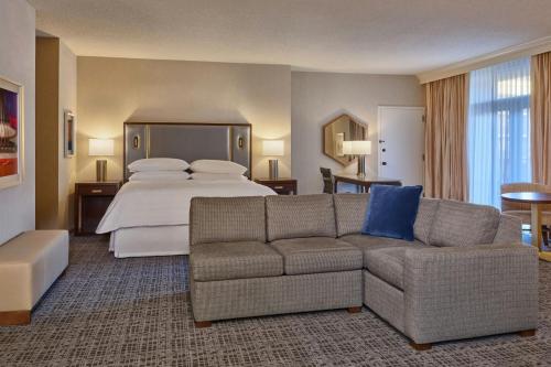 a large hotel room with a bed and a couch at Sheraton Music City Nashville Airport in Nashville
