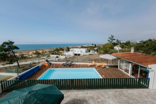 a house with a swimming pool and the ocean at Casa das Camarinhas in Murtinheira