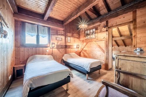 two beds in a room with wooden walls at Gand chalet montagne 30 personnes in Bernex