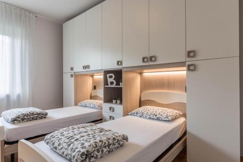 two beds in a room with white cabinets at appartamento casa stefi n2 in Malcesine