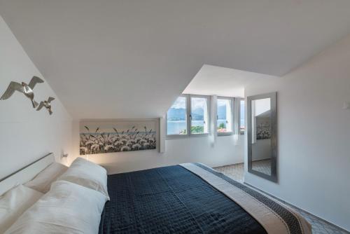 a white bedroom with a bed and a mirror at Casa Royale Appartamento Aria in Lierna