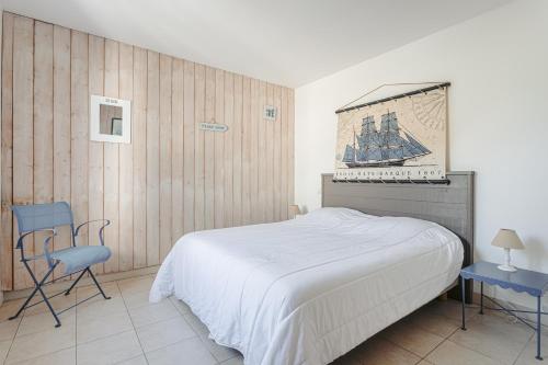 una camera da letto con un letto bianco e una sedia blu di Pingettes 4 a Le Bois-Plage-en-Ré