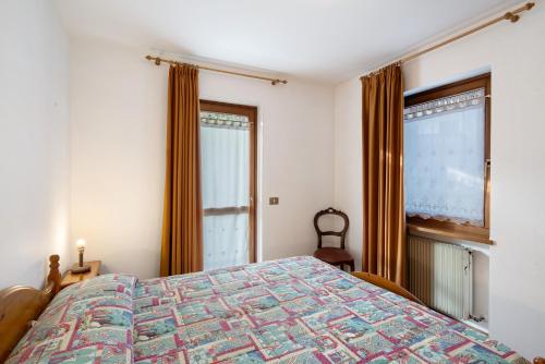 a bedroom with a bed and two windows at Residence Malibu Appartamento 8 in Falcade