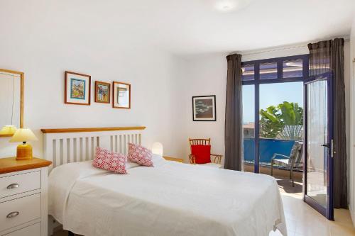 a bedroom with a white bed and a balcony at Free Airport Shuttle and Parking in San Bartolomé
