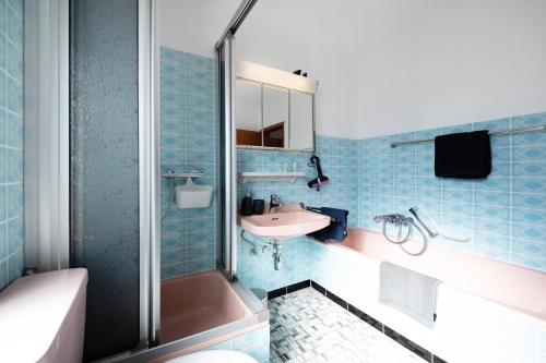a bathroom with blue tiles and a sink and a shower at Ut Huuske in Dorsel