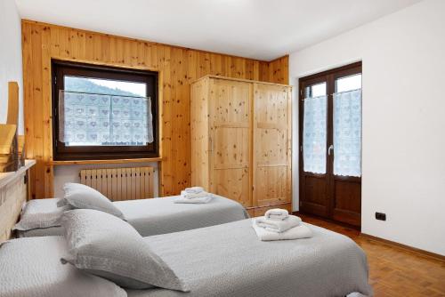 two beds in a room with wooden walls at Maison Le Cré Appartamento 3 in Introd