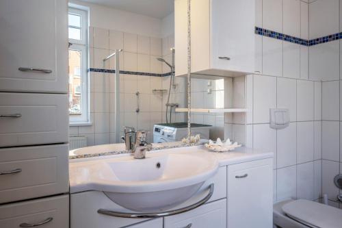 a white bathroom with a sink and a toilet at Haus Übersee Wohnung Fidji in Travemünde