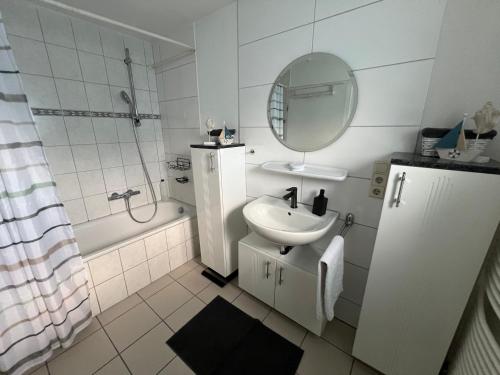a white bathroom with a sink and a mirror at Ferienhaus Almir in Haselünne