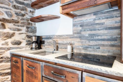 a kitchen with a sink and a stone wall at Appartement ô Canton in Val Cenis