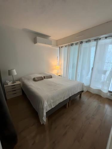 a white bedroom with a bed and two windows at Plage du Couchant in La Grande Motte