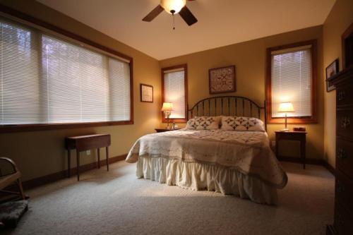 a bedroom with a bed with two tables and two windows at Pine Hill · Pine Hill in Sherwood Forest in Rosman