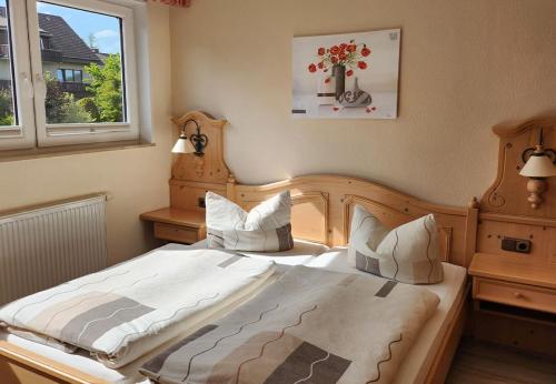 a bedroom with a large bed with white sheets and a window at Gästehaus Nietmann_ Ferienwohnung 7 in Altenau