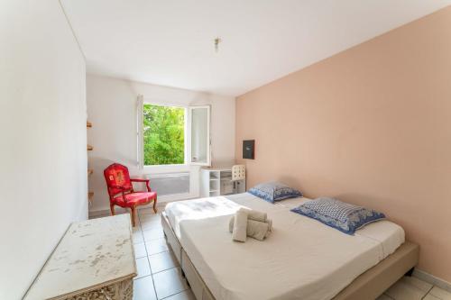 a bedroom with two beds and a red chair at Plein coeur du Luberon in Apt