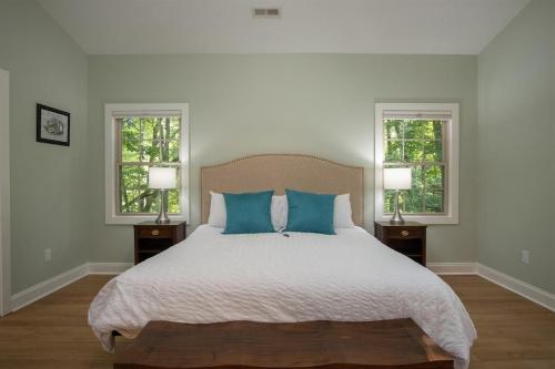 a bedroom with a bed with blue pillows and two windows at Hummingbird Hideaway · Hummingbird Hideaway in Connestee Falls in Brevard