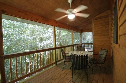 a porch with a table and chairs and a ceiling fan at White Squirrel`s Nest · White Squirrel`s Nest in Sherwood Forest in Rosman
