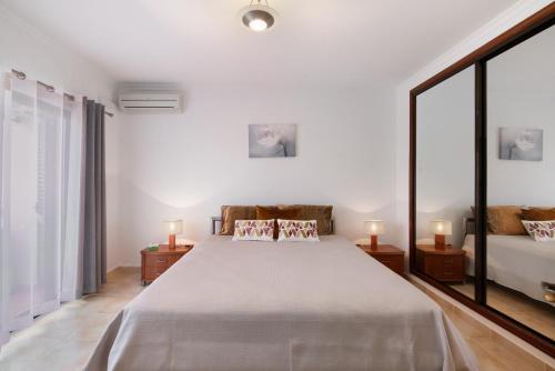 a white bedroom with a large bed and a couch at Villa Neves in Albufeira