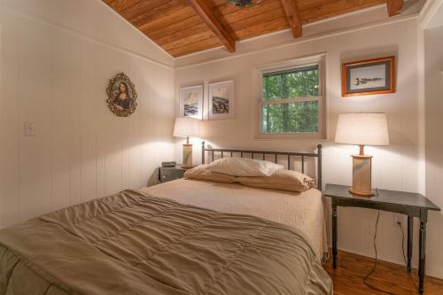 a bedroom with a bed and two lamps and a window at The Deep Forest Green Cottage · The Deep Forest Green Cottage in Cedar Mountain
