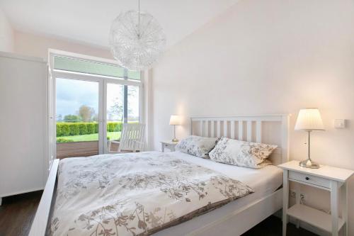 a white bedroom with a bed and a window at Haus Eiderblick in Horst