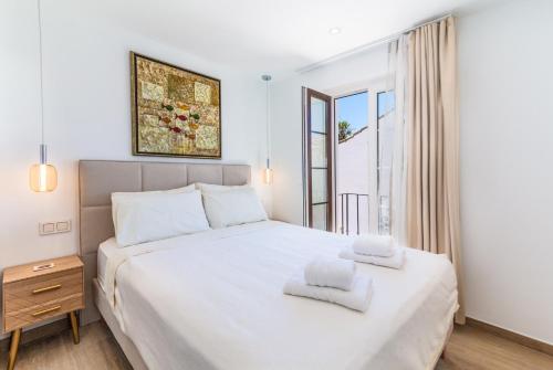 a bedroom with a white bed with two towels on it at Townhouse El Naranjal in Marbella