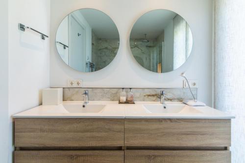 a bathroom with two sinks and two mirrors at Townhouse El Naranjal in Marbella
