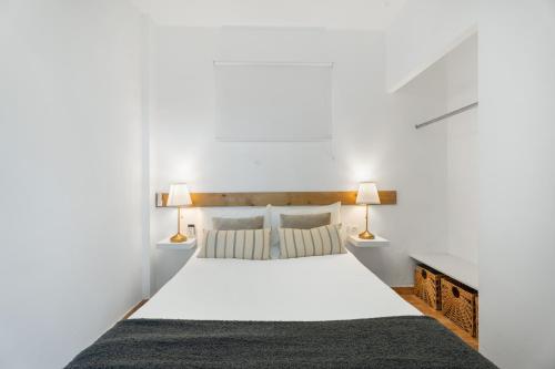 a bedroom with a white bed with two lamps at La Atalaya in Adeje