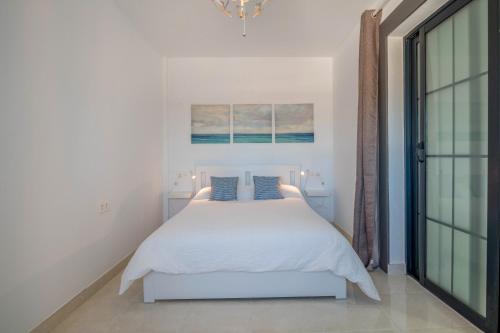 a white bedroom with a bed and a chandelier at Villa Esmeralda in Lanzarote