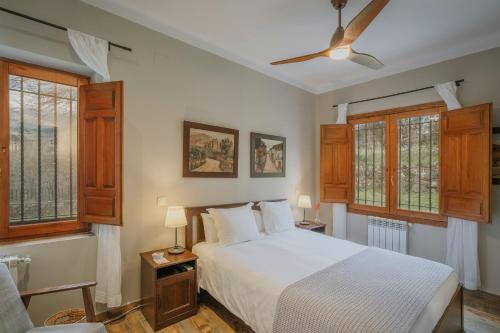 a bedroom with a white bed and some windows at Finca El Aguilojo in Mombeltrán