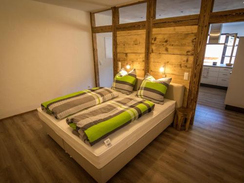 a bedroom with a large bed with green and brown pillows at Ferienwohnung Maulbetsch in Alpirsbach