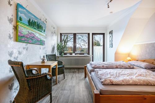 a bedroom with two beds and a table and a chair at Ferienwohnung am Töschenbach in Hennstedt