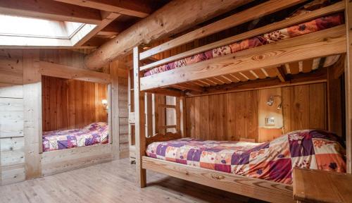 two bunk beds in a room with wooden walls at Chalet Les Liouès in Sollières-Sardières