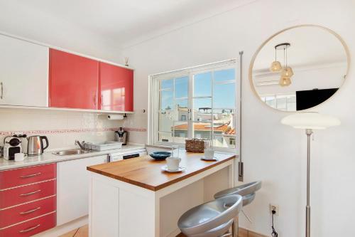a kitchen with red cabinets and a table with a chair at A Casa de Emy in Cabanas de Tavira