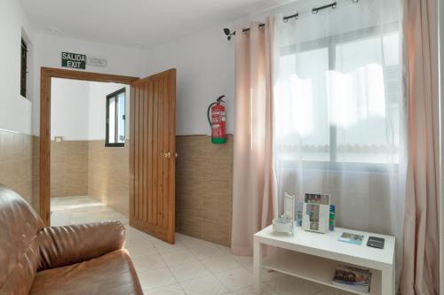a living room with a couch and a table and a window at Hostal Avenida in Conil de la Frontera
